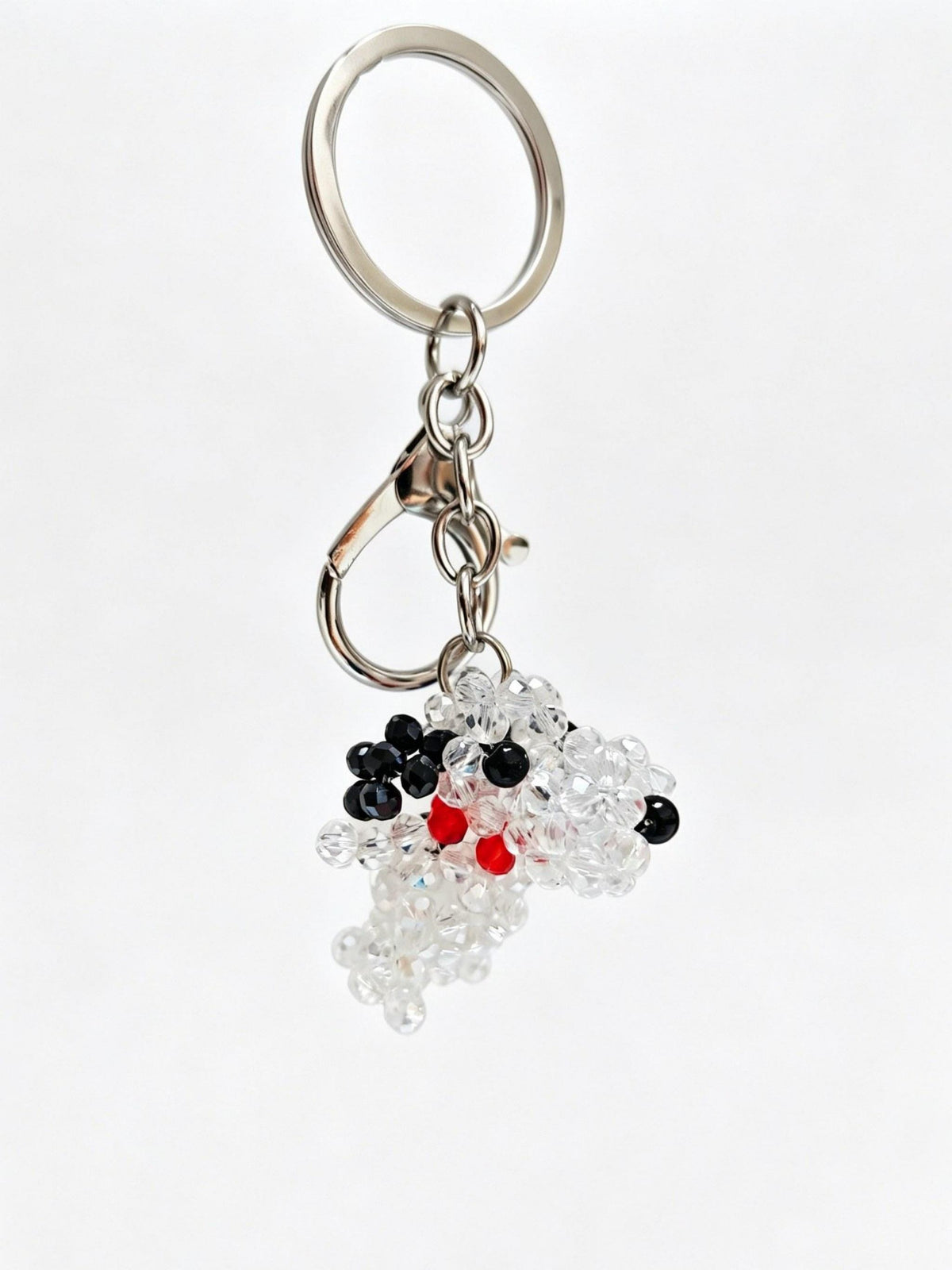 A silver metal keychain with a clasp and key ring, featuring a dangling beaded charm shaped like a stylized face made of clear, black, and red beads, on a plain white background.