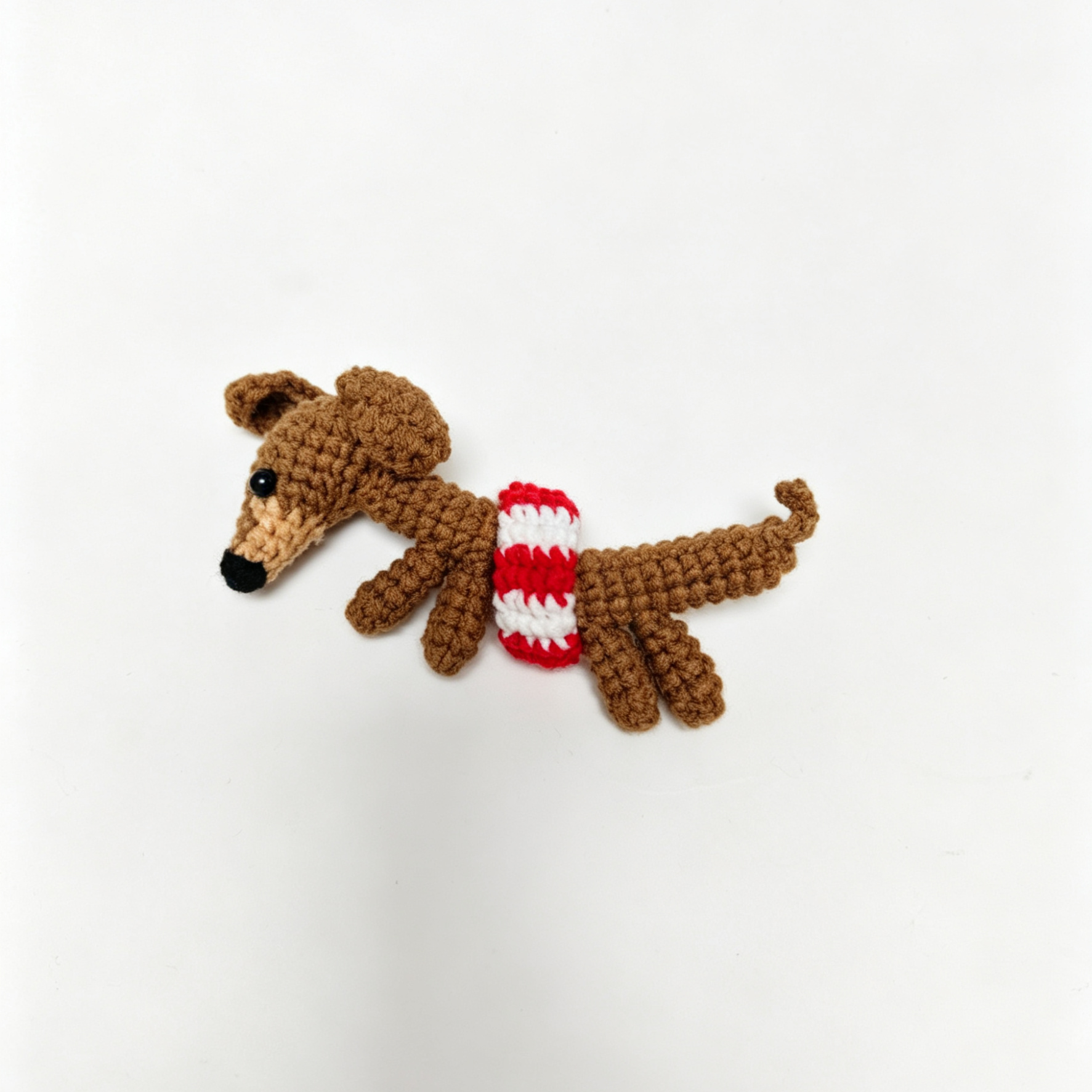 Crocheted dog with a striped sweater on a white background